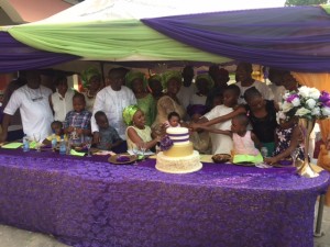 The celebrant, Mrs Adeline Ndoma Egba assisted by family, cuts her 90th birthday cake