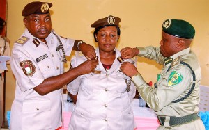MR WILLIAM OCHE,  (LEFT) COMPTROLLER, BAYELSA COMMAND , NIGERIA IMMIGRATION SERVICE  AND MR CHIABUA  VICTOR-UCHE  (RIGHT)COMPTROLLER Bayelsa command, Nigerian prison service decorating mrs ngozi acholonu, newly elevated deputy comptroller of immigration with her new rank at a ceremony at the bayelsa command headuarers of the immigration service in yenagoa